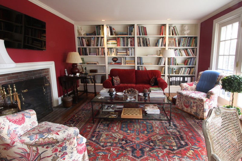 Painted living room and reading room, with red and white walls and painted bookshelves.